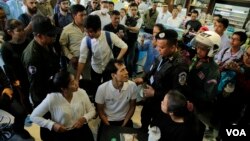 Police officers are seen talking to Cambodian activists having coffee at a convenience store where the late political commentator Kem Ley was killed in 2017, Phnom Penh, Cambodia, July 10, 2019. (Aun Chhengpor/VOA Khmer) 