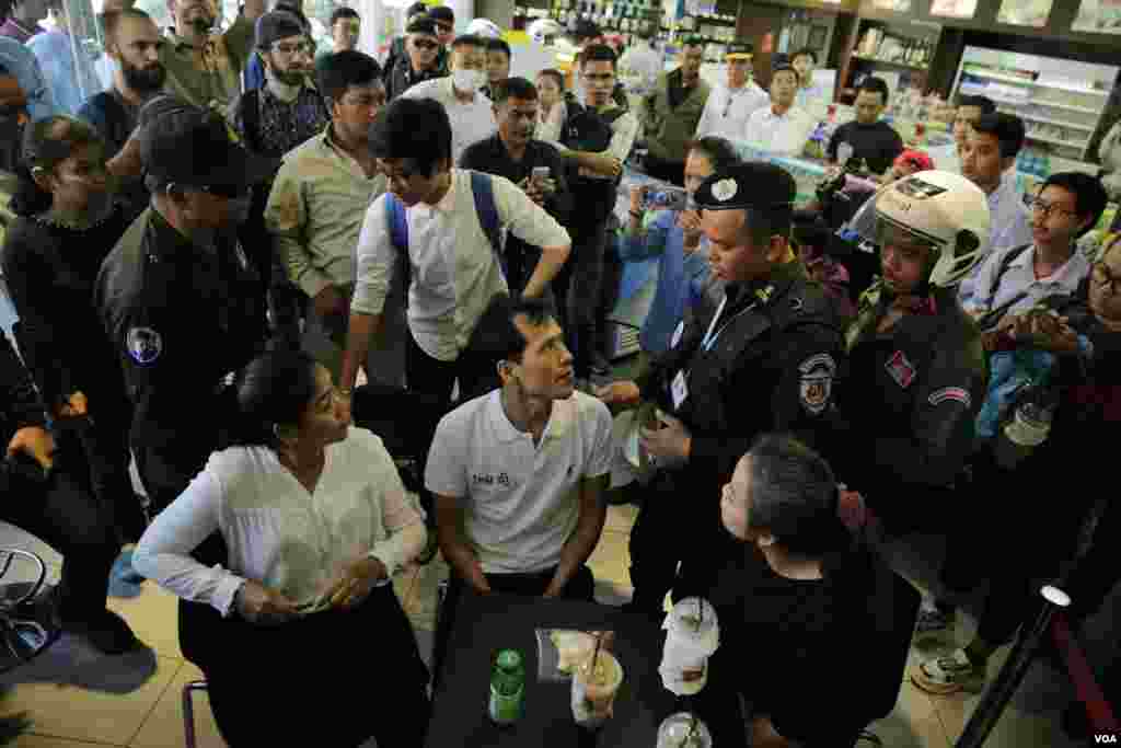 កងកម្លាំងនគរបាលចូលមកសាកសួរសកម្មជនសង្គមស៊ីវិល ដែលនៅអង្គុយក្រេបកាហ្វេ កាលពីថ្ងៃទី១០ ខែកក្កដា ឆ្នាំ២០១៩ ក្នុងហាងលក់ទំនិញទីដែលលោក កែម ឡី ត្រូវបានគេបាញ់ស្លាប់ កាលពីឆ្នាំ២០១៦។ (អូន ឆេងប៉រ)