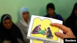 FILE - A counselor holds up cards used to educate women about female genital mutilation (FGM) in Minia, Egypt, June 13, 2006. 