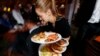 A waitress fights to deliver plates of breakfast through local Republicans gathered to watch the inauguration of Donald Trump, Jan. 20, 2017, in Denver. 