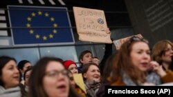 Wanawake wakiwa na mabango yao juu wamekusanyika nje ya Bunge la Ulaya wakipinga uonevu dhidi ya tofauti ya mishahara baina yao na wanaume, uvunjifu wa amani na kukosekana haki katika maeneo mengi, mjini Brussels, Ijumaa, Machi 8, 2019.