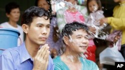 Born Samnang, left, and Sok Sam Oeun are blessed with holly water by a Buddhist monk at a Buddhist pagoda after their release from a main prison in Prey Sar, on the outskirts of Phnom Penh, Cambodia, Thursday, Sept. 26, 2013. The two Cambodian men wrongly convicted for the 2004 murder of a prominent opposition activist walked free on Thursday, one day after the country's Supreme Court ordered their release. (AP Photo/Heng Sinith)
