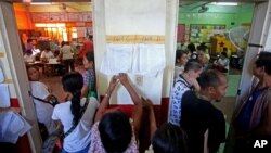 Filipinos check for their names on registration lists to vote as polling stations prepare to close at a school in suburban Manila, Philippines on Monday, May 9, 2016. Millions of Filipinos went to election centers Monday to pick a new president, vice president and thousands of other officials amid tight security across the country. (AP Photo/Lino Escandor II)