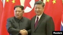 Shugaban Koriya ta Arewa Kim Jong Un shhands ya sha hannu da shugaban China Xi Jinping yayin ziyararsa