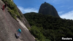 ຄາເຊຍ ໂວລາຣີ ໄວ 82 ປີ ພວມປີນພູ ອູຣກາ ໃນນະຄອນ ຣີໂອ ດີ ຈາແນໂຣ ຂອງບຣາຊີລ ໂດຍການຊ່ອຍຈາກຄູສອນ ຣາຟາແອລ ເຣເນ, ເມື່ອວັນທີ 8 ທັນວາ 2024. (REUTERS/Pilar Olivares)