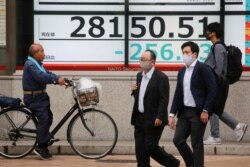 People walk by an electronic stock board of a securities firm in Tokyo, May 19, 2021.