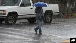 A man carries an umbrella as he walks across a street in San Francisco, Nov. 9, 2015.