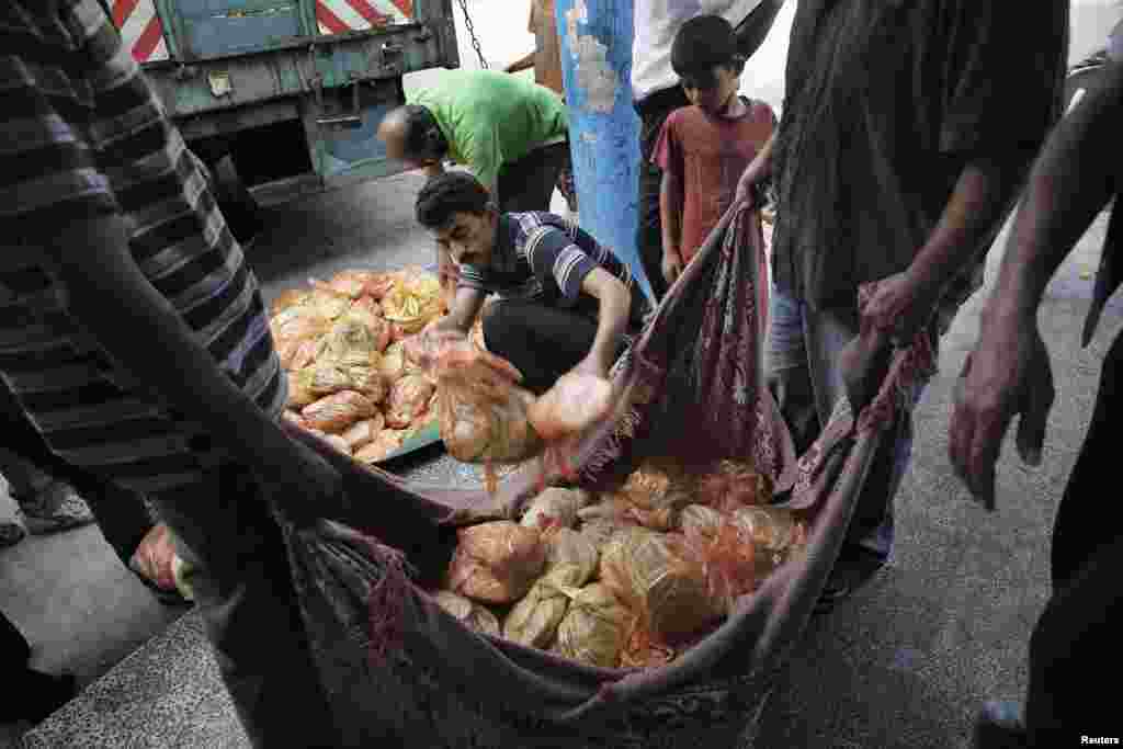 Palestinian men prepare to distribute bread at a United Nations-run school acting as a shelter for residents who have fled their homes during an Israeli ground operation, in Jabaliya in the northern Gaza Strip, July 29, 2014.