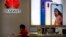 FILE - A sales clerk looks at his smartphone in a Huawei store at a shopping mall in Beijing Wednesday, July 4, 2018. 
