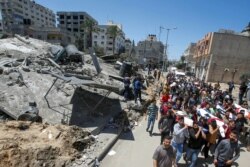 Mourners carry the bodies of Palestinians who were killed amid a flare-up of Israeli-Palestinian violence, during their funeral near the remains of a building destroyed in Israeli airstrikes, at the Beach refugee camp, in Gaza City May 15, 2021.