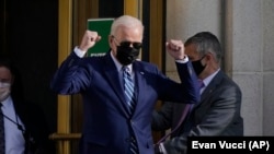 在首都华盛顿郊外的马里兰州贝塞斯达市，美国总统拜登在完成例行体检结束后走出沃尔特·里德国家军事医疗中心时做着手势。( 2021年11月19日)