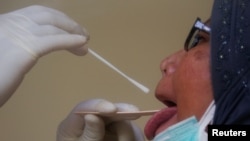Seorang pekerja sedang melakukan tes usap Covid-19 terhadap seorang perempuan di Jakarta, 30 April 2020. (Foto: Reuters)