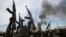 FILE - Rebel fighters hold up their rifles as they walk in front of a bushfire in a rebel-controlled territory in Upper Nile State, South Sudan February 13, 2014.