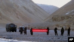 FILE - In this May 5, 2013, file photo, Chinese troops hold a banner which reads "You've crossed the border, please go back" in Ladakh, India. India says it is ready to hold talks with China with both sides pulling back their forces to end a standoff along a disputed territory high in the Himalayan mountains.