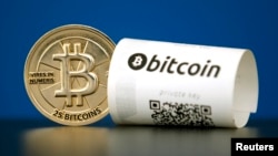 FILE - A Bitcoin (virtual currency) paper wallet with QR codes and a coin are seen in an illustration picture taken at La Maison du Bitcoin in Paris, France, May 27, 2015.