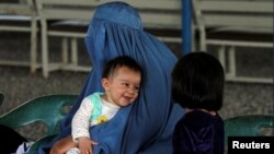 An Afghan refugee woman waits with her children to be repatriated to Afghanistan, at the United Nations High Commissioner for Refugees office on the outskirts of Peshawar, Pakistan, April 3, 2017. 