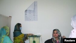 A woman casts her ballot at a polling station during voting to elect lawmakers for legislative assembly in Pakistan-administered Kashmir, in Muzaffarabad, July 25, 2021. 