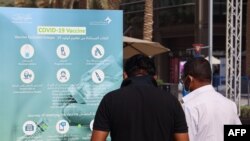 People look at an information placard in front of a designated COVID-19 vaccination center at Dubai's financial center district, in the United Arab Emirates, on Jan. 24, 2021.