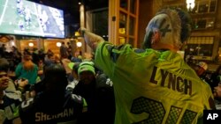 Stunned Seattle Seahawks fan Dustin Pittis points at a TV monitor, Feb. 1, 2015, as he watches the end of Super Bowl XLIX at a bar in Seattle, Washington.