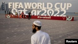 A man is pictured in front of a FIFA World Cup Qatar 2022 sign on November 17, 2022. (REUTERS/Marko Djurica)