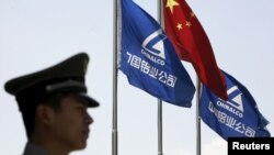 FILE - A security guard stands in position in front of the company's and Chinese flags outside the headquarters of Aluminum Corp of China (Chinalco) in Beijing in this June 5, 2009 file photo. 