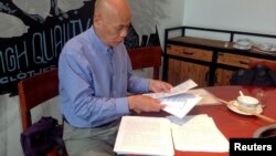 FILE - Xu Xiaoshun, the father of activism blogger Wu Gan, who was detained in what is known as the "709" crackdown, looks through documents about his son's case in a restaurant in Jiangsu Province, China, June 12, 2017.