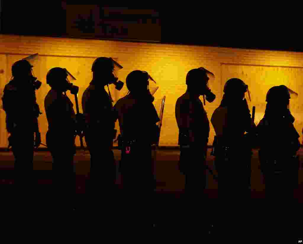 Police wait to advance after tear gas was used to disperse a crowd during a protest for Michael Brown in Ferguson, Missouri, Aug. 17, 2014.