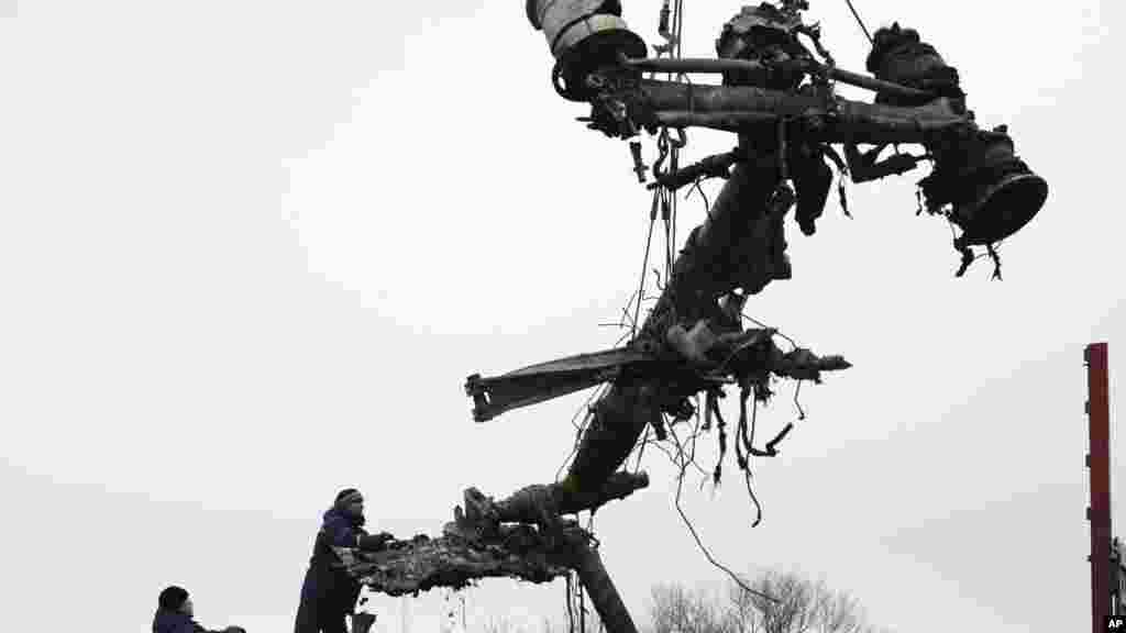 Recovery workers in rebel-controlled eastern Ukraine load debris from the crash site of Malaysia Airlines Flight 17, in Hrabove, Ukraine, Nov. 16, 2014.