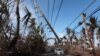 Cars drive under a partially collapsed utility pole, after the island was hit by Hurricane Maria in September, in Naguabo, Puerto Rico Oct. 20, 2017.