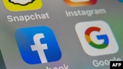 (FILES) This file picture taken on October 1, 2019 shows the logos of mobile apps Facebook and Google displayed on a tablet in Lille. - Australia announced in 2020 it will begin forcing Google and Facebook to pay news companies for content.
