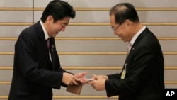 South Korea's ruling Saenuri Party chairman Hwang Woo-yea, right, and Japanese Prime Minister Shinzo Abe exchange their business cards prior to their meeting at the prime minister's residence in Tokyo, Wednesday, Jan. 9, 2013. (AP Photo/Itsuo Inouye, Pool)