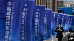 资料照：一名男子走过上海街头插满的宣传旗帜：“中国式现代化与世界”。 （2023年4月21日）