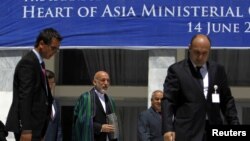 Afghan President Hamid Karzai (C) arrives for a group photo with ministers from other Heart of Asia member countries at the end of a conference in Kabul June 14, 2012.