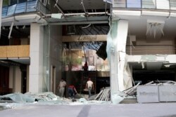 People are seen at the entrance to a damaged building near the site of an explosion Tuesday that hit the seaport of Beirut, Lebanon, Aug. 6, 2020.