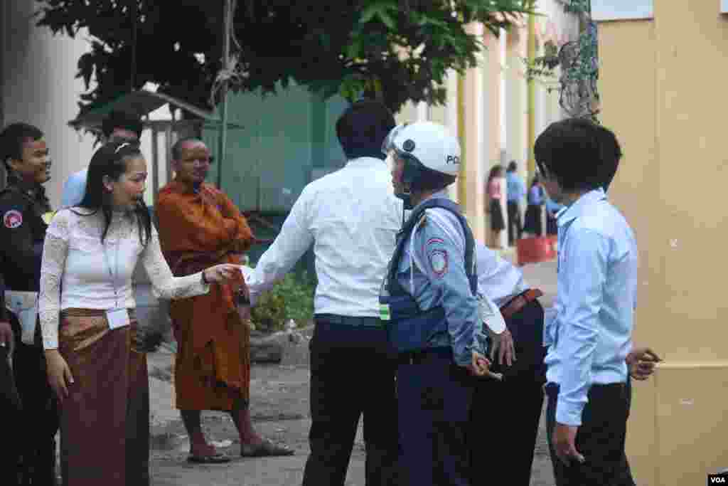 នគរបាលកំពុង​ឈរ​រក្សា​សន្តិសុខ​ ខណៈ​អនុរក្ស​កំពុង​ឈរ​ចាំ​ត្រួត​ពិនិត្យ​បេក្ខជន​​មុន​នឹង​អនុញ្ញាត​ឱ្យ​ចូល​ក្នុង​មណ្ឌល​ប្រលង​វិទ្យាល័យ​ព្រះស៊ីសុវត្ថិ​ កាល​ពី​ថ្ងៃ​ទី​២៤​ សីហា​&nbsp;ឆ្នាំ២០១៥។&nbsp;​(ស៊ូ​ ពិសែន/VOA)