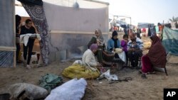 Anggota keluarga Abu Jarad, yang mengungsi akibat pemboman Israel di Jalur Gaza, memanggang roti di tenda kamp darurat di daerah Muwasi, Gaza selatan. 