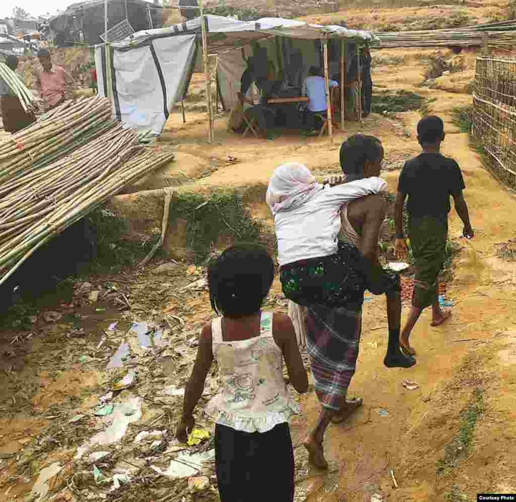 Rohingya refugees walk along a litter-strewn path next to makeshift tents at a camp in Bangladesh. (Photo courtesy of Dr. Imran Akbar)