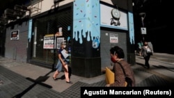 Pedestrians walk past out-of-business stores which display "For rent" signs, near the Buenos Aires' Obelisk, Argentina April 6, 2021. (REUTERS/Agustin Marcarian)