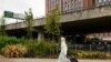 FILE - A student wearing full-body PPE due to the COVID-19 pandemic walks toward the Coventry University Library at the beginning of the new academic year, at Coventry University, in Coventry, central England, Sept. 23, 2020.
