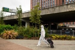 FILE - A student wearing full-body PPE due to the COVID-19 pandemic walks toward the Coventry University Library at the beginning of the new academic year, at Coventry University, in Coventry, central England, Sept. 23, 2020. (AFP)