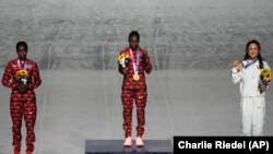 Le médaillé d'or du marathon féminin Peres Jepchirchir du Kenya (centre), la médaillée d'argent Brigid Kosgei (à g.), du Kenya et la médaillée de bronze Molly Seidel des États-Unis, le 8 août à Tokyo, au Japon. 