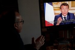 Giuseppe Fonsino, listens to the speech of French President Emmanuel Macron on TV, in Ville d'Avray, near Paris, Monday, April 13, 2020. Macron said that the country's coronavirus lockdown will be extended till May 11.