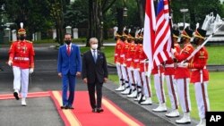 Malaysian Prime Minister Muhyiddin Yassin, center, walks with Indonesian President Joko Widodo as they inspect honor guards during their meeting at Merdeka Palace in Jakarta, Indonesia, Friday, Feb. 5, 2021. (Agus Suparto, Indonesian President Palace via AP)
