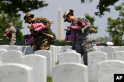 FILE - Members of the Old Guard, with the Washington Memorial in the back, place flags in front of every headstone at Arlington National Cemetery in Arlington, Va., Thursday, May 26, 2016. Soldiers were to place nearly a quarter of a million U.S. flags at the cemetery as part of a Memorial Day tradition. ( AP Photo/Jose Luis Magana)