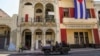 FILE - Special forces police patrol the streets as they drive past a large Cuban flag hanging from the facade of a building, in Havana, Cuba, July 21, 2021.