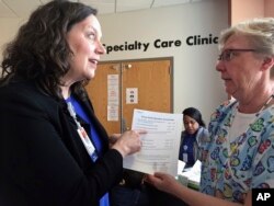 FILE - In this May 2, 2017 photo, Patsy Stinchfield, left, senior director of infection control at Children's Minnesota in Minneapolis, talks with nurse Kathy Kaul about a measles screening questionnaire that hospital staff are using to assess a patient's