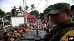 A soldier looks on as housewives stand in line for rations and water in Juchitan, Oaxaca state, Mexico, a zone heavily affected by Thursday's magnitude 8.2 earthquake, Sept. 9, 2017. 