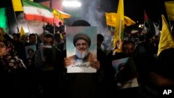 A cleric holds a poster of slain Hezbollah leader Hassan Nasrallah during an anti-Israeli gathering celebrating Iran's missile strike against Israel at Felestin Square in Tehran, Iran, Oct. 1, 2024.