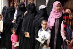 FILE - Women and children queue to receive food rations at a charity kitchen in Sanaa, Yemen, July 19, 2020.