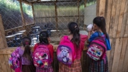 Students wait for their instructor as they look into their classroom flooded the night before by a heavy rain, in the makeshift settlement Nuevo Queja, Guatemala, Tuesday, July 6, 2021. (AP Photo/Rodrigo Abd)